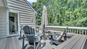 A wooden deck with outdoor furniture, including chairs and a table, and a covered umbrella.