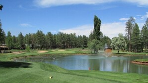A golf course with a pond, trees, and a wooden structure. - Beautiful condo on Pinetop Lakes Golf Course (Pinetop)