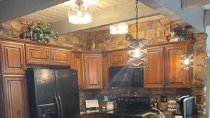 A kitchen with wooden cabinets, a black refrigerator, a microwave, and a granite countertop. - Beautiful condo on Pinetop Lakes Golf Course (Pinetop)