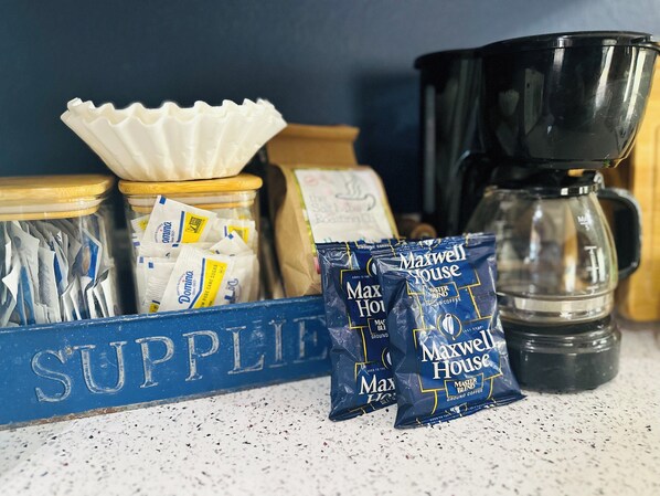 Equipo para preparar café, con cafetera, jarra, dosificador y sobres de café molido.