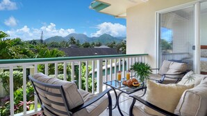 Ein Balkon mit Blick auf Berge, ein Tisch mit Frühstücksangebot und zwei Stühle.