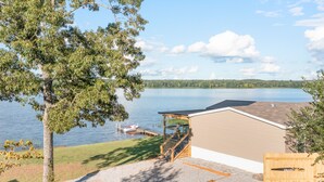 A lakeside property with a wooden deck, a boat dock, and a building with a sloped roof. - PJinx and Grace Peaceful Lake front 3BR/2ba (Shelby)