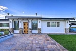 Una casa moderna de dos pisos con entrada de ladrillo, una puerta principal y un pequeño jardín delantero.