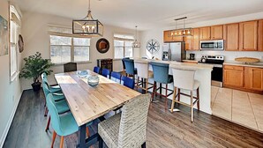 Une cuisine spacieuse avec des meubles en bois, un îlot central et un coin repas doté de chaises bleues.