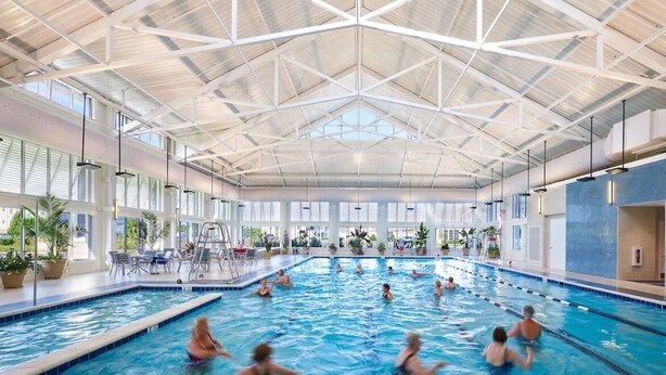 Une piscine intérieure dotée d’un haut plafond et de grandes fenêtres.