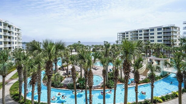 Un complexe hôtelier doté de plusieurs piscines, entouré de palmiers, avec une plage et une vue sur l’océan.