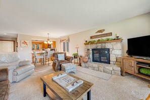 A living room with a fireplace, leather sofas, a coffee table, and a television.