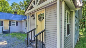 A small, single-story house with a yellow front door, a black front porch railing, and a blue metal roof. - Stylish Mountain Home Near Ski, Golf + Manchester! (Bondville)
