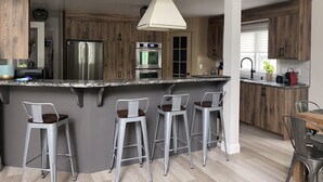 Una cocina moderna con una isla central, electrodomésticos de acero inoxidable y taburetes de bar.