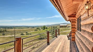 A wooden deck with a metal railing overlooking a rural landscape.