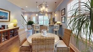 A dining area with wicker chairs, a round table, and a hanging light fixture. - Garden Cottage 23 - Beautifully decorated cottage close to pool and beach! (Jekyll Island)