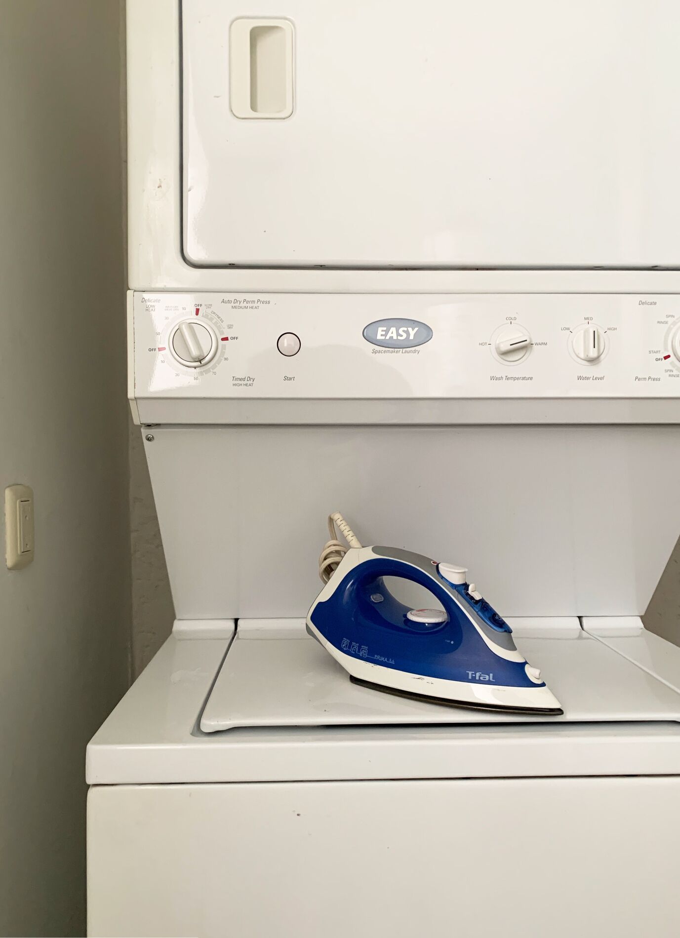 A white washing machine with a blue iron on top.