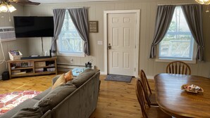 A living room with a sofa, TV, bookshelf, dining table, and two windows with curtains. - Minutes from Mammoth Cave and Nolin Lake! (Mammoth Cave)