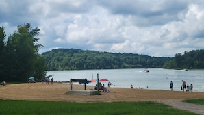 A lakeside beach with a sandy shore, a wooden dock, and a forested hill in the background. - Minutes from Mammoth Cave and Nolin Lake! (Mammoth Cave)