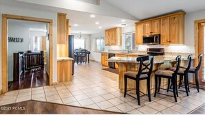 A spacious kitchen with wooden cabinets, a granite countertop, and a bar area with stools.