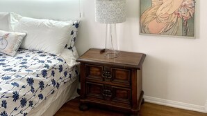 Ein Schlafzimmer mit einem Bett, einem Nachttisch, einer Lampe und einem Wandbild.