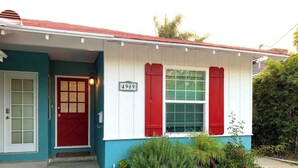 Ein Haus mit roter Tür, einem Schild mit der Nummer 4909 und einem Fenster mit roten Rollläden.