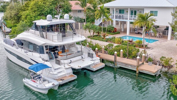 A large yacht docked at a marina with a pool and a house in the background. - P98 - 75ft dock with shore power, 4 bed, 4 bath home w/private pool in Sombrero Beach Neighborhood. (Marathon)