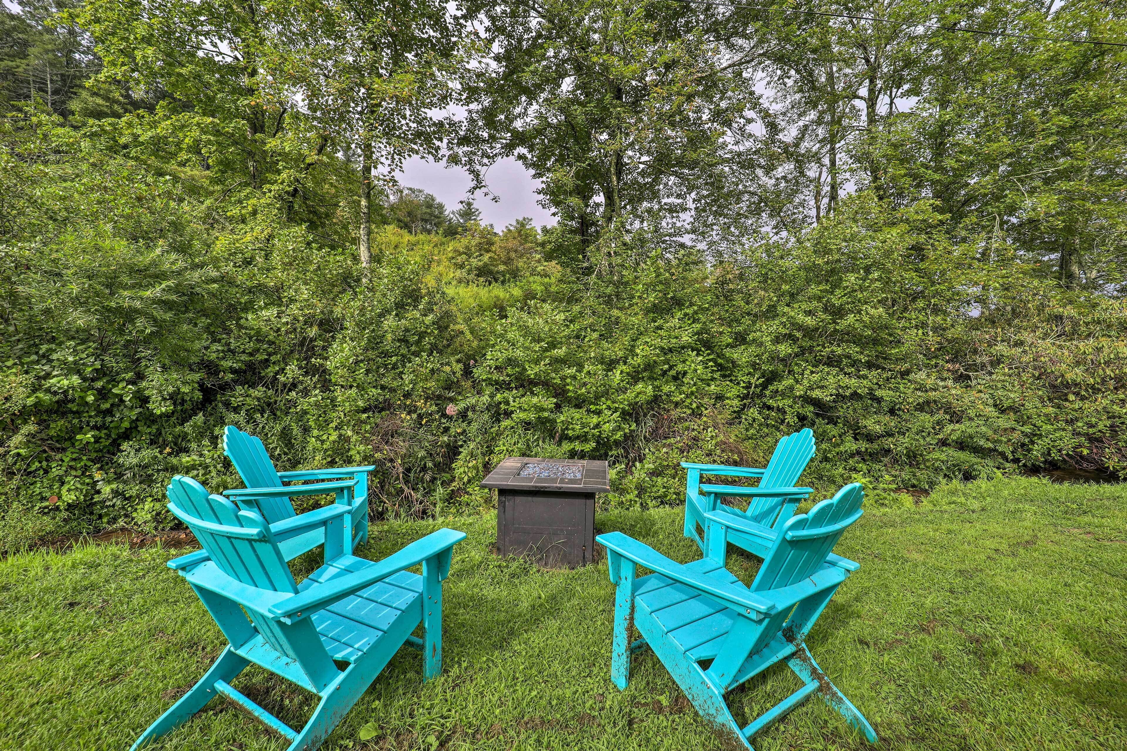 Two turquoise Adirondack chairs facing a small wooden structure in a lush green garden.