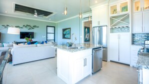 A modern kitchen with white cabinetry, a central island, stainless steel appliances, and pendant lighting.