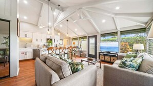 A spacious living area with a sofa, a dining table, and a kitchen in the background. - Beautifully Furnish Kaanapali Cottage near Beach - International Colony Club 13 (Lahaina)