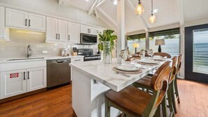 A modern kitchen with white cabinets, a central island, and pendant lighting. - Beautifully Furnish Kaanapali Cottage near Beach - International Colony Club 13 (Lahaina)