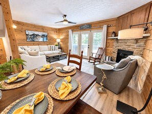 A cozy interior with a dining area, a fireplace, and a living room with a sofa and a chair.