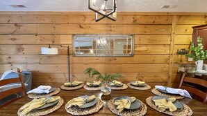 A wooden dining table set for six with placemats, plates, and folded napkins. - Ski In/Out, Watch Slope frm Hot Tub, 6BR, 3 Kings, PS5, Tesla, Rec Rm-Loggers 12 (Snowshoe)