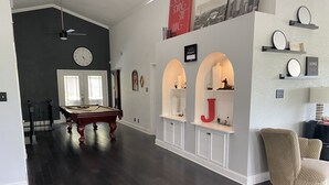Un salon spacieux avec une table de billard, une grande horloge et un fauteuil confortable.
