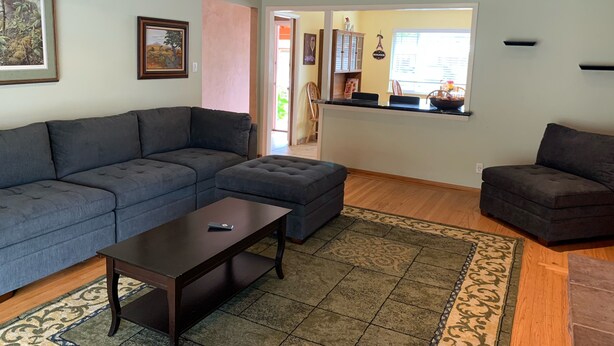 Ein Wohnzimmer mit einem Ecksofa, einem Couchtisch und einem Teppich.