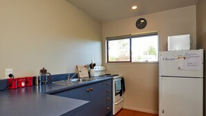 A compact kitchen with a sink, stove, and a refrigerator. - Spacious 1 bedroom Cottage (Kaikoura)