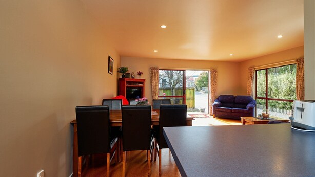 A spacious living area with a dining table, chairs, a sofa, and a television. - Spacious 1 bedroom Cottage (Kaikoura)