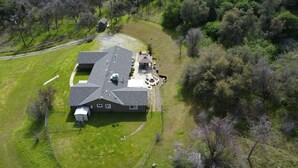 A large house with a sloped roof, a fenced yard, and a small garden area.