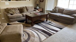 A living room with two sofas, a coffee table, and a patterned rug.