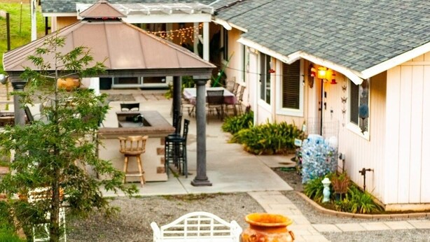 A covered patio area with a table and chairs, a white bench, and a large pot.