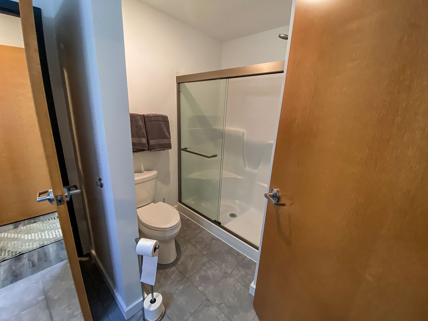 A bathroom with a toilet, a glass shower enclosure, and a towel rack.
