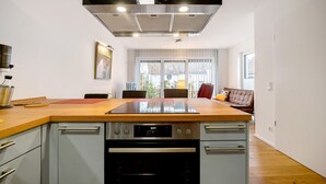 A modern kitchen with a central island, stainless steel appliances, and a large window providing natural light. - Holiday Apartment at the "Gustavsburg" Castle with Wi-Fi & Terrace (Homburg)