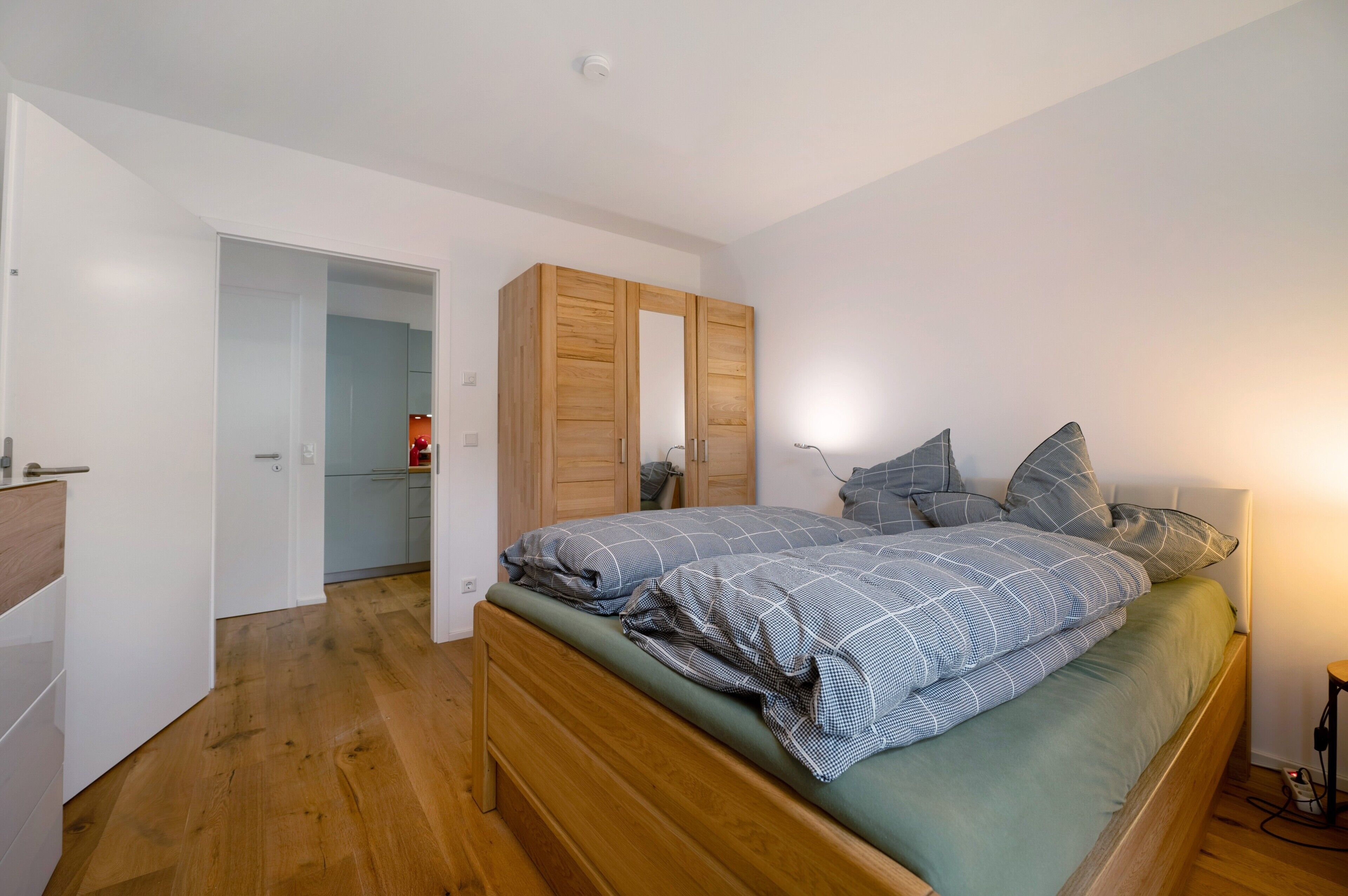 A bedroom with a wooden bed, a wardrobe, and a door leading to a bathroom.