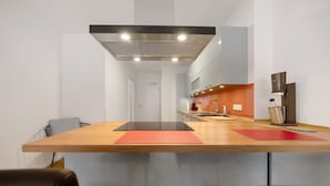 A modern kitchen with a central island, a stainless steel range hood, and a countertop with a coffee machine. - Holiday Apartment at the "Gustavsburg" Castle with Wi-Fi & Terrace (Homburg)