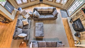 Ein geräumiges Wohnzimmer mit grauem Ecksofa, Poufs und einem Kamin aus Stein.