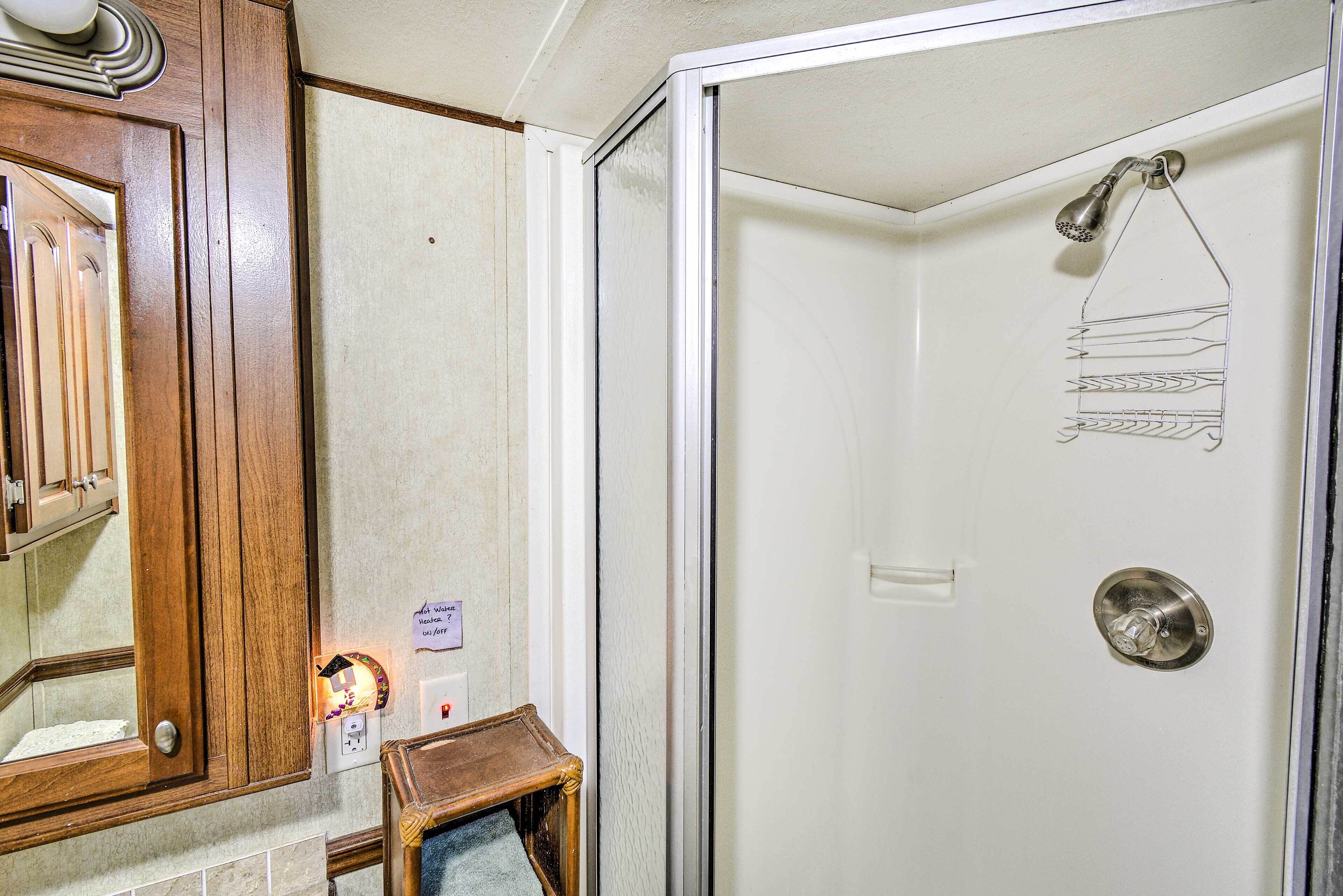 Un baño con un armario de madera, un perchero y una ducha con cabezal metálico.