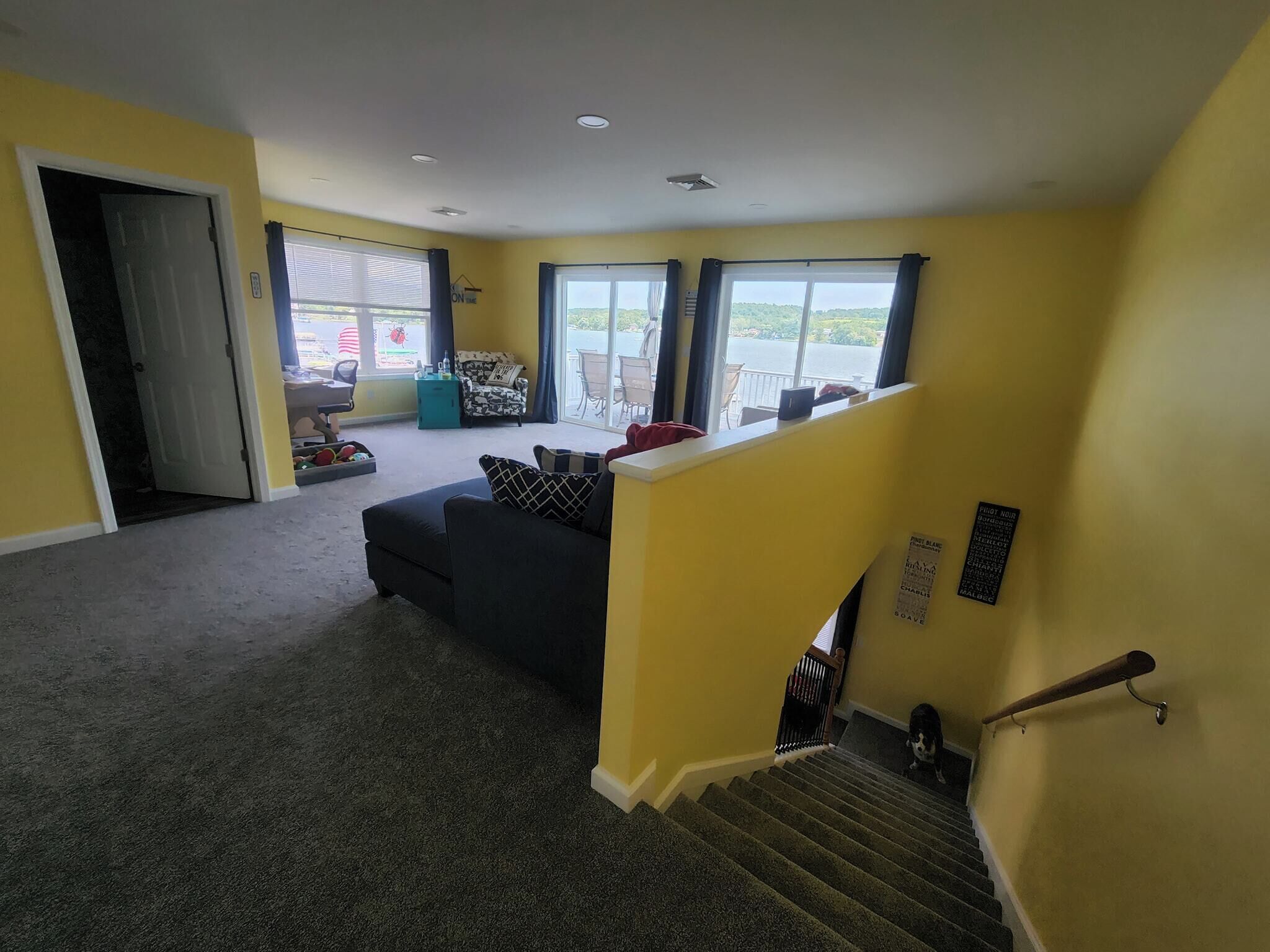 Sala de estar com sofá, escada e vista para o exterior.