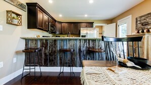 Una cocina con armarios de madera oscura, un refrigerador de acero inoxidable y una zona de bar con taburetes.