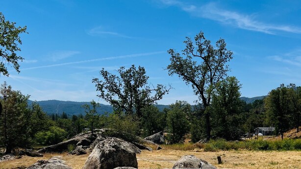 Un jacuzzi en un entorno natural, con cielo despejado y árboles al fondo.