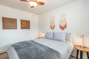 Ein Schlafzimmer mit einem Bett, zwei Wand-Dreamcatchern, einem Deckenventilator und zwei Nachttischen mit Lampen.