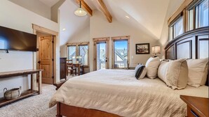 A bedroom with a large bed, wooden headboard, a desk, and a chair. There is a window with a view of the outside. - Beautiful 3 bedroom with private hot tub, walkable to town and trails (Frisco)