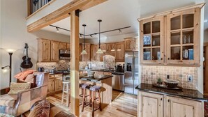 A spacious kitchen with wooden cabinets, a central island, and a dining area with a sofa and chairs. - Beautiful 3 bedroom with private hot tub, walkable to town and trails (Frisco)