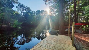 A wooden dock extending into a calm body of water, surrounded by dense trees and a clear sky. - ★Bluegill Cottage★ by the lake - Kayak, pedal boat, fishing, private dock (Goodrich)
