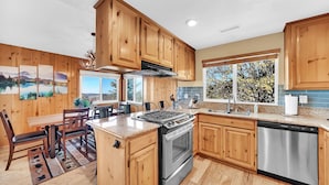 A modern kitchen with wooden cabinets, a stainless steel stove, and a dishwasher. - 3-bedroom cabin near Santa's Village-13 minutes from Snow Valley Mountain Resort (Running Springs)