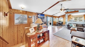 A spacious living area with wooden walls, a ceiling fan, and a fireplace. - 3-bedroom cabin near Santa's Village-13 minutes from Snow Valley Mountain Resort (Running Springs)
